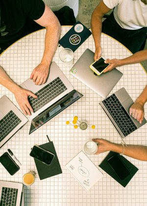 Top view of a team collaborating with laptops, phones, and notes in a modern office.
